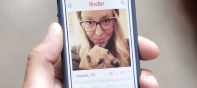 a person holding a phone with a woman holding a dog on the screen