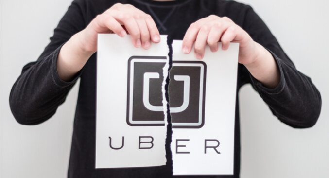 a person holding a torn Uber sign