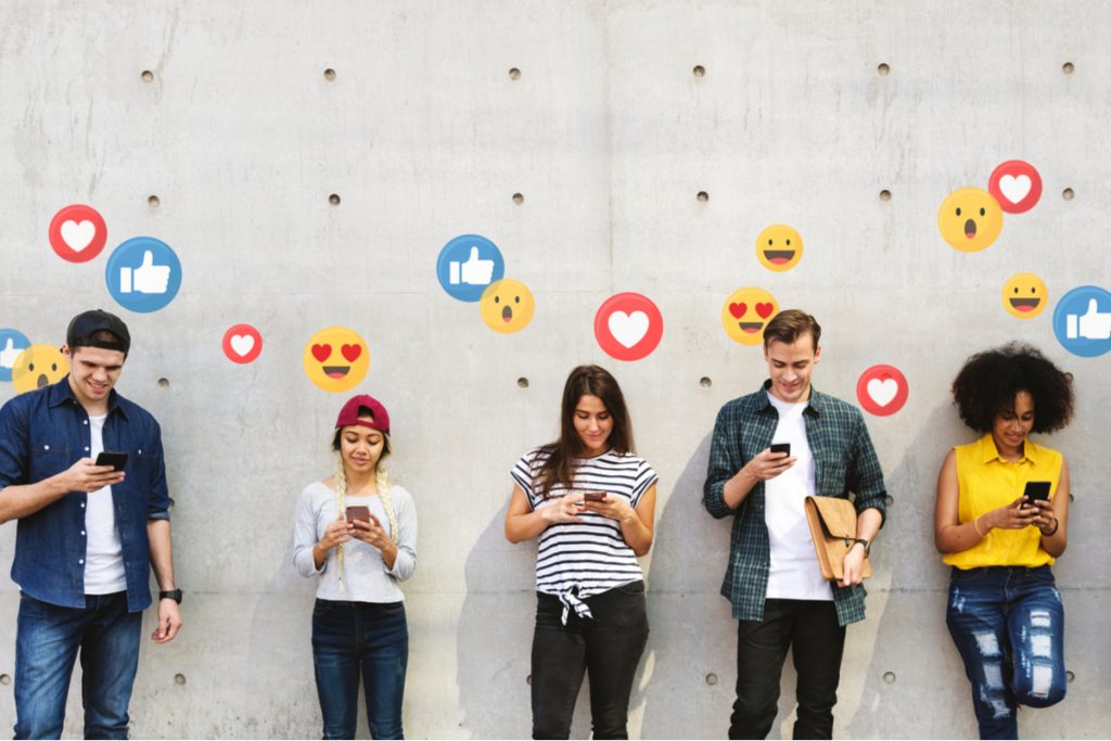 a group of people standing in front of a white wall with emojis